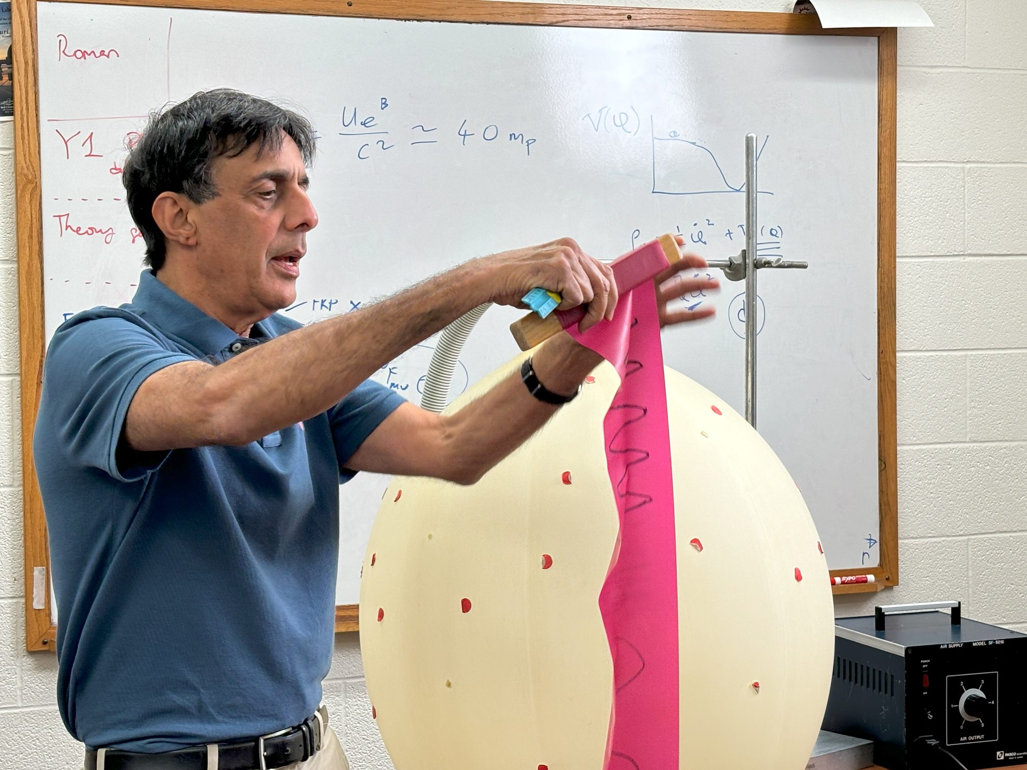 2025 5 Sigma Physicist Honoree Bharat Ratra engaging with students during a physics demo involving a giant balloon.
